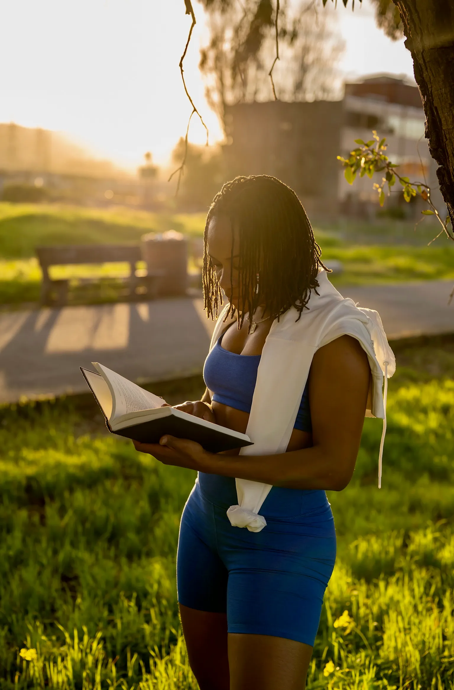 Coach Ugochi reading outdoors in athletic wear during a rest moment between workouts